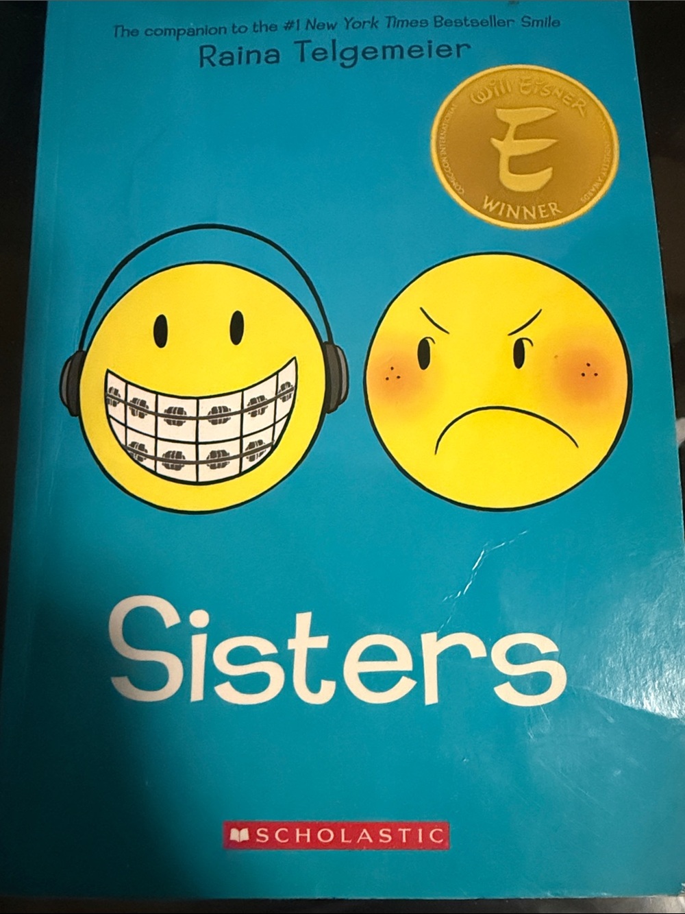 Sisters by Raina Telgemeier - Bright Teal Cover with Yellow Emojis